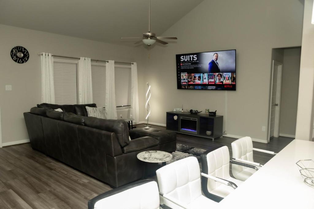 a living room with a black couch and a tv at Cozy Room with Private bath in Richmond, TX in Richmond