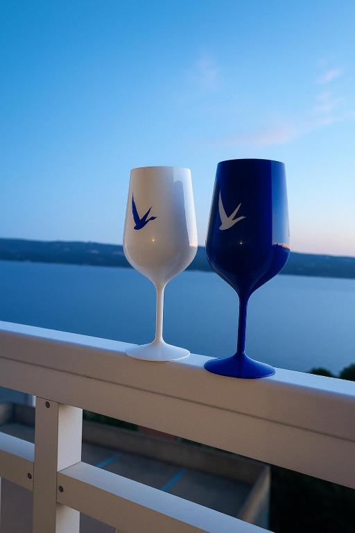 two wine glasses sitting on a railing with a view at Villa Roing R in Stanići