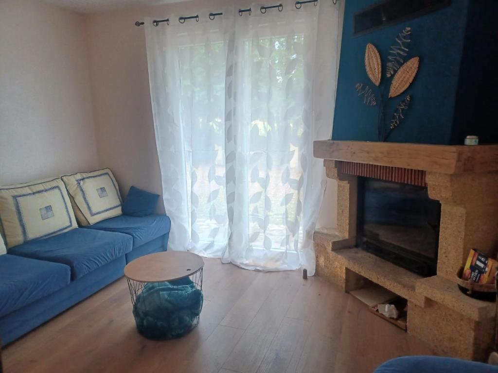 a living room with a blue couch and a fireplace at Maison de campagne à Château-Chervix in Château-Chervix