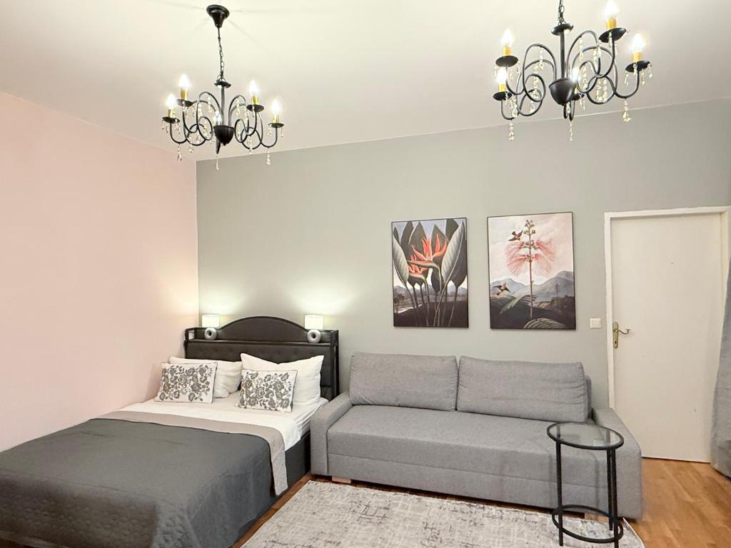 a bedroom with a bed and a couch and a chandelier at Apartment near Meidling in Vienna
