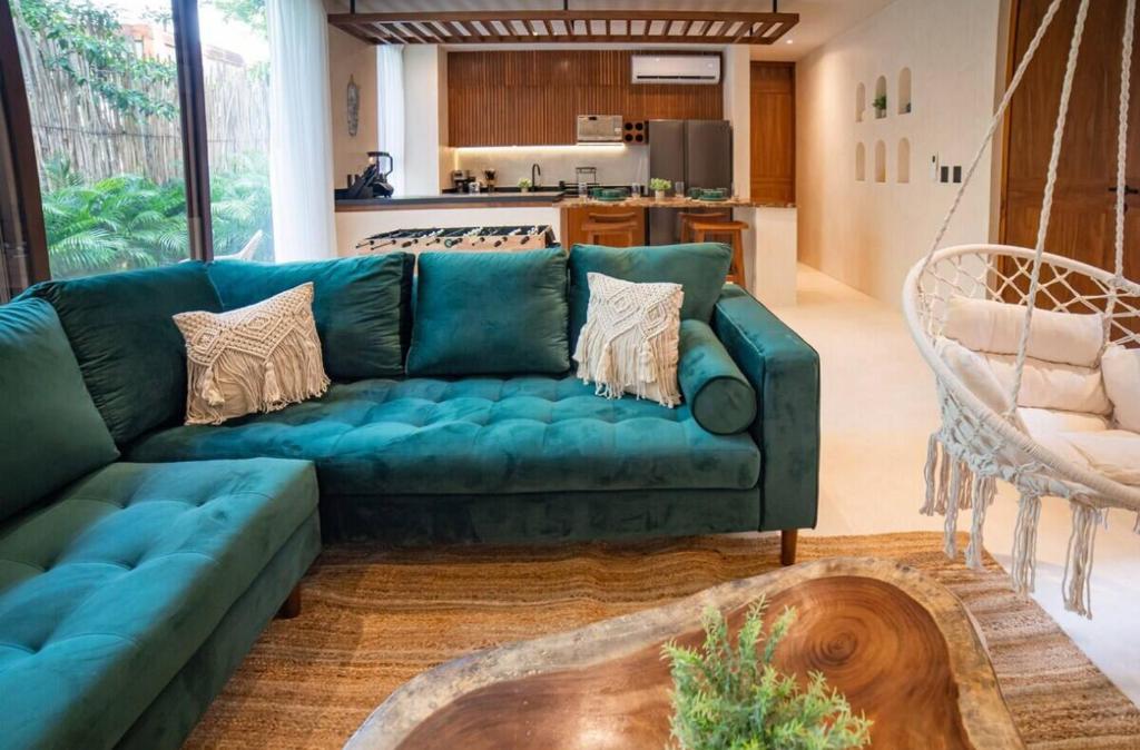 ein Wohnzimmer mit einer grünen Couch und einer Küche in der Unterkunft Kaíoro Tulum in Tulum