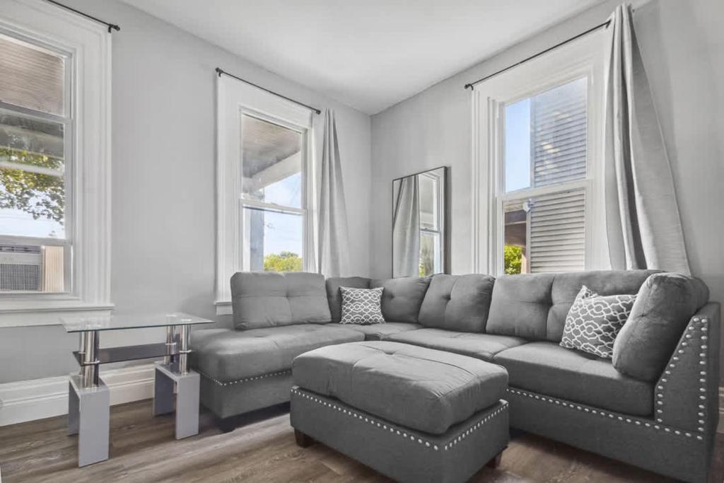 a living room with a couch and a table and windows at 5BR Home-Walk to Niagara Falls & Aquarium in Niagara Falls