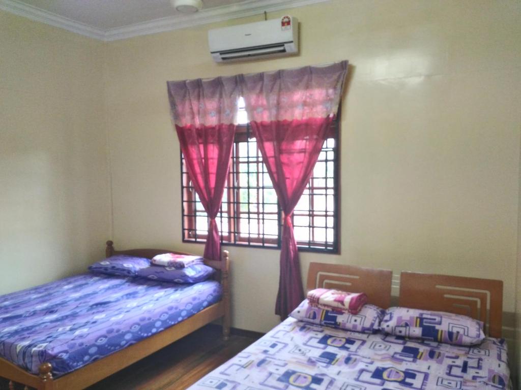 two beds in a room with a window at Z&R HOMESTAY in Kota Bharu