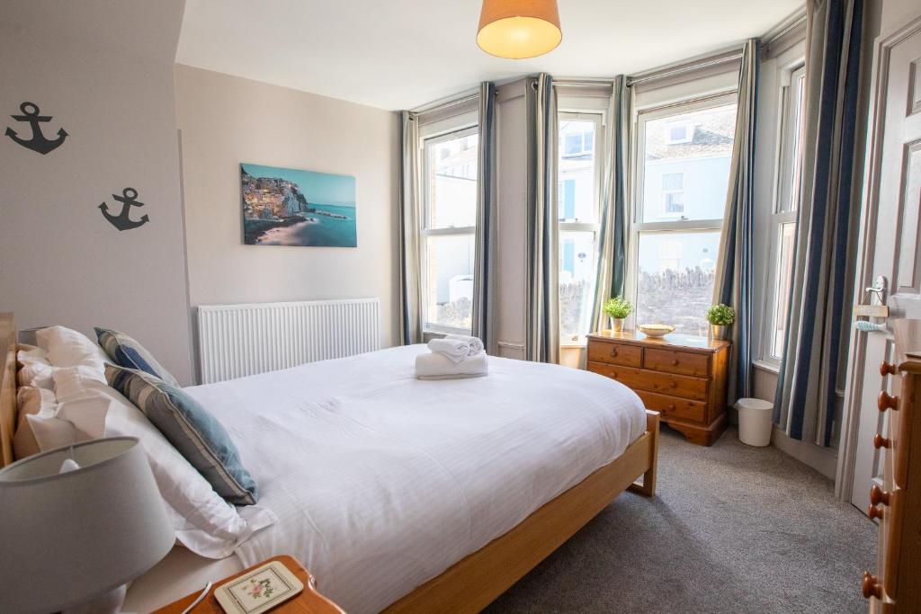 ブリクサムにあるHarbour View- Cosy Maisonette, Close to Brixham Harbourの大きなベッドと2つの窓がある寝室