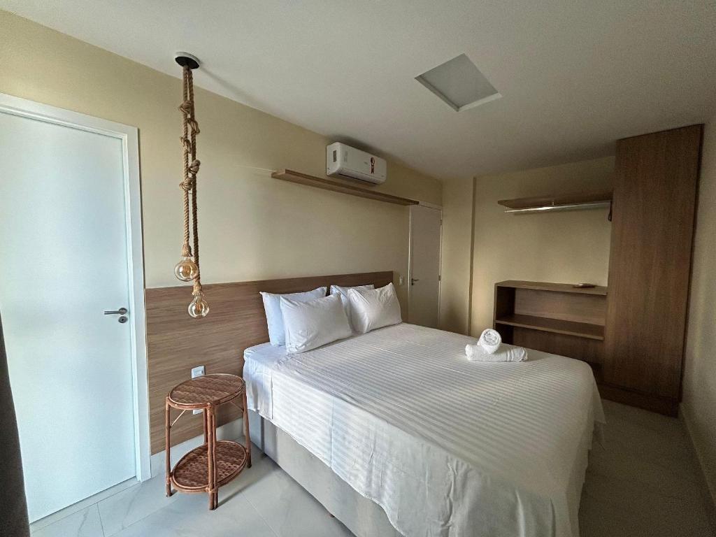 ein Hotelzimmer mit einem Bett mit einer weißen Tagesdecke in der Unterkunft Apartamento 40m da praia Maragogi vista mar in Maragogi