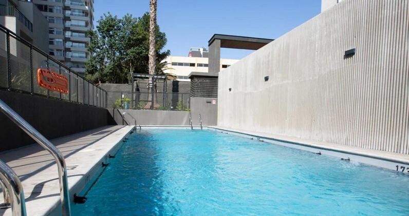 a large blue swimming pool next to a building at Depto moderno en Nuñoa cerca Metro y Barrio Italia in Santiago