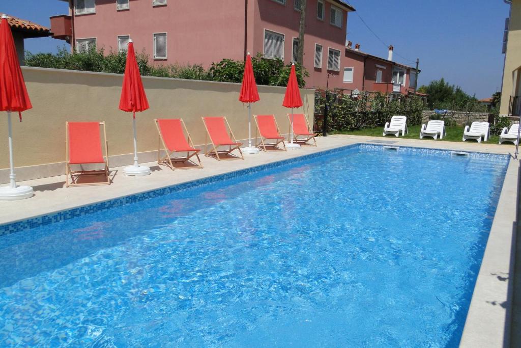 a swimming pool with chairs and red umbrellas at Villa Ester in Umag