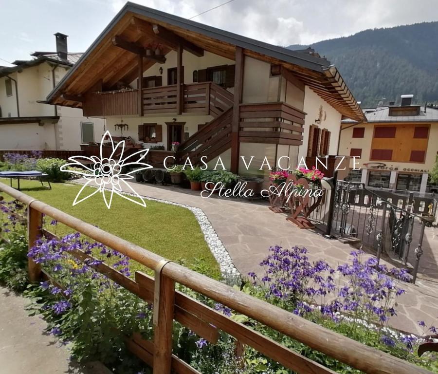 a house in the mountains with a fence and flowers at Stella Alpina Holiday Home in Auronzo di Cadore