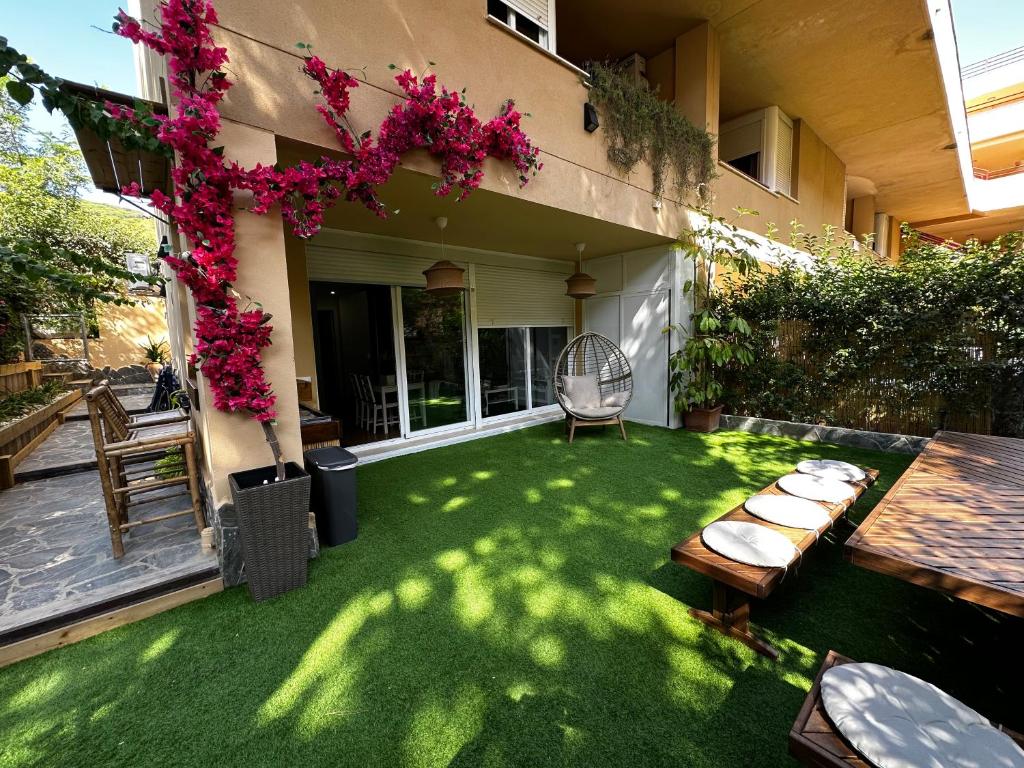a backyard with a green lawn with a table and chairs at BASTINAZO ALOHADREAM - PREMIUM - Dúplex Lujo Recién Reformado con Jardín, Piscina, Parking, Aire Acondicionado - Los Caños de Meca - 50m playa in Los Caños de Meca