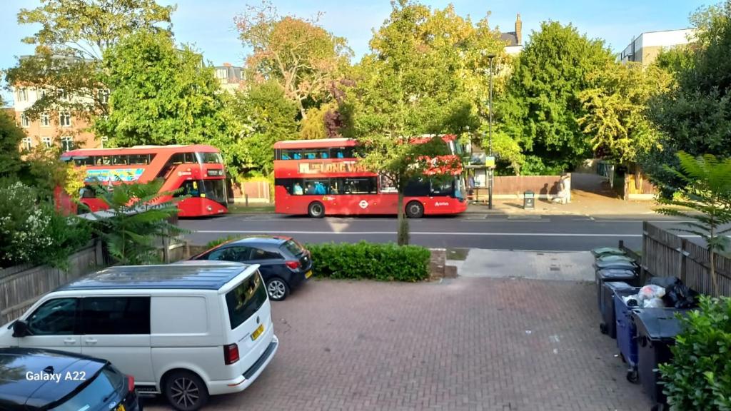 two red buses parked in a parking lot with cars at Room Imperial in London