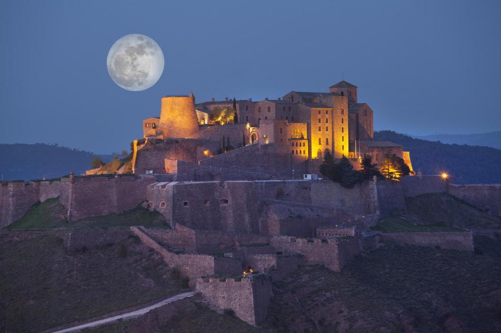 um castelo numa colina à noite com lua cheia em Parador de Cardona em Cardona