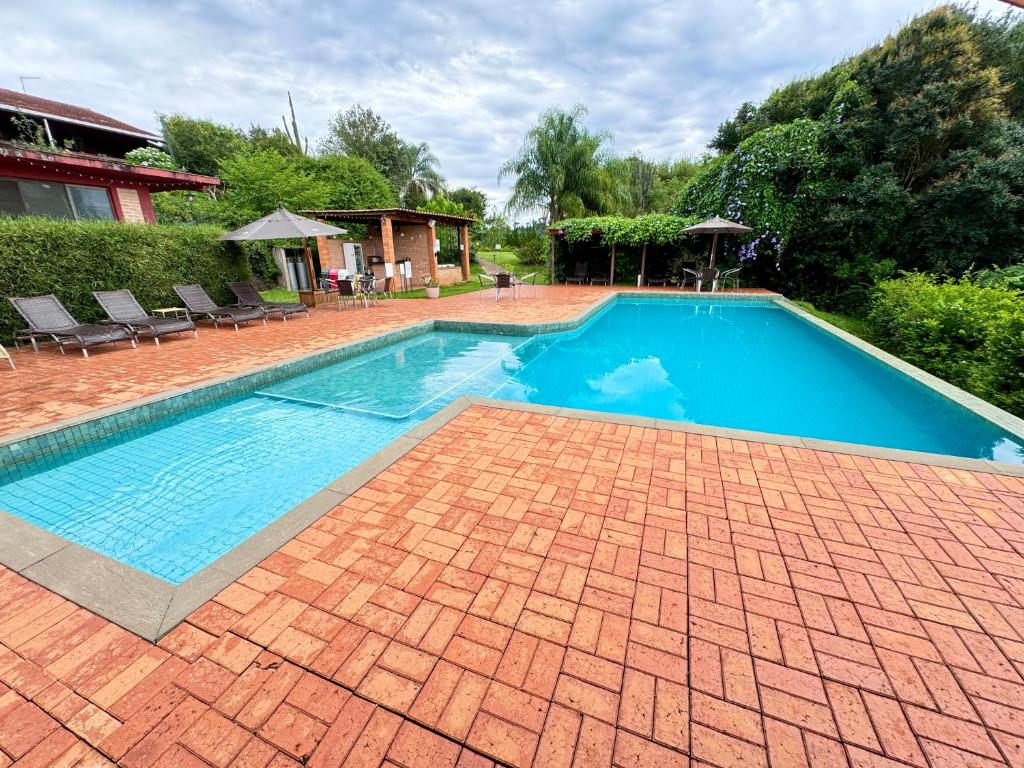 a large swimming pool with a brick floor and a brickkeredkered at Hotel Fazenda Vale Alvorada in Cascavel