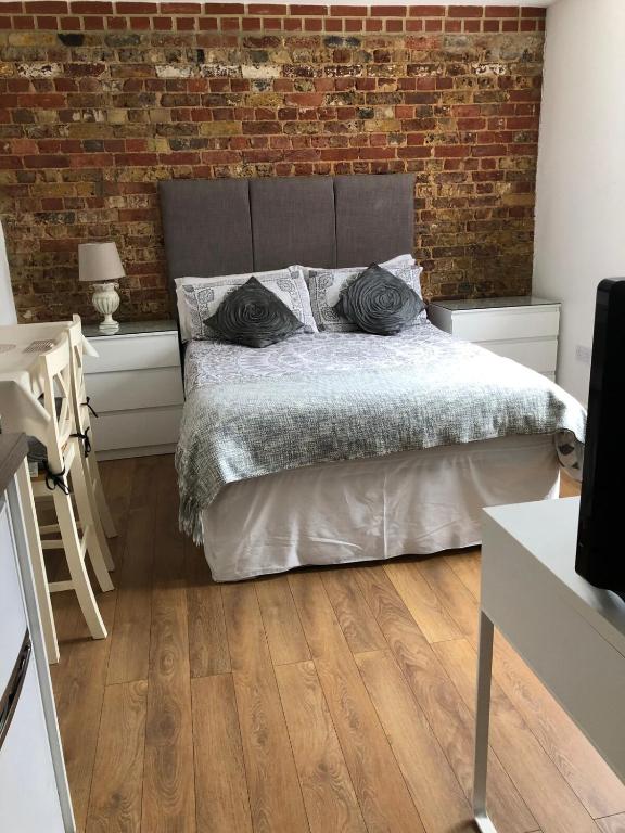a bedroom with a bed and a brick wall at Stunning Studio1, Banstead with free off st parking in Banstead