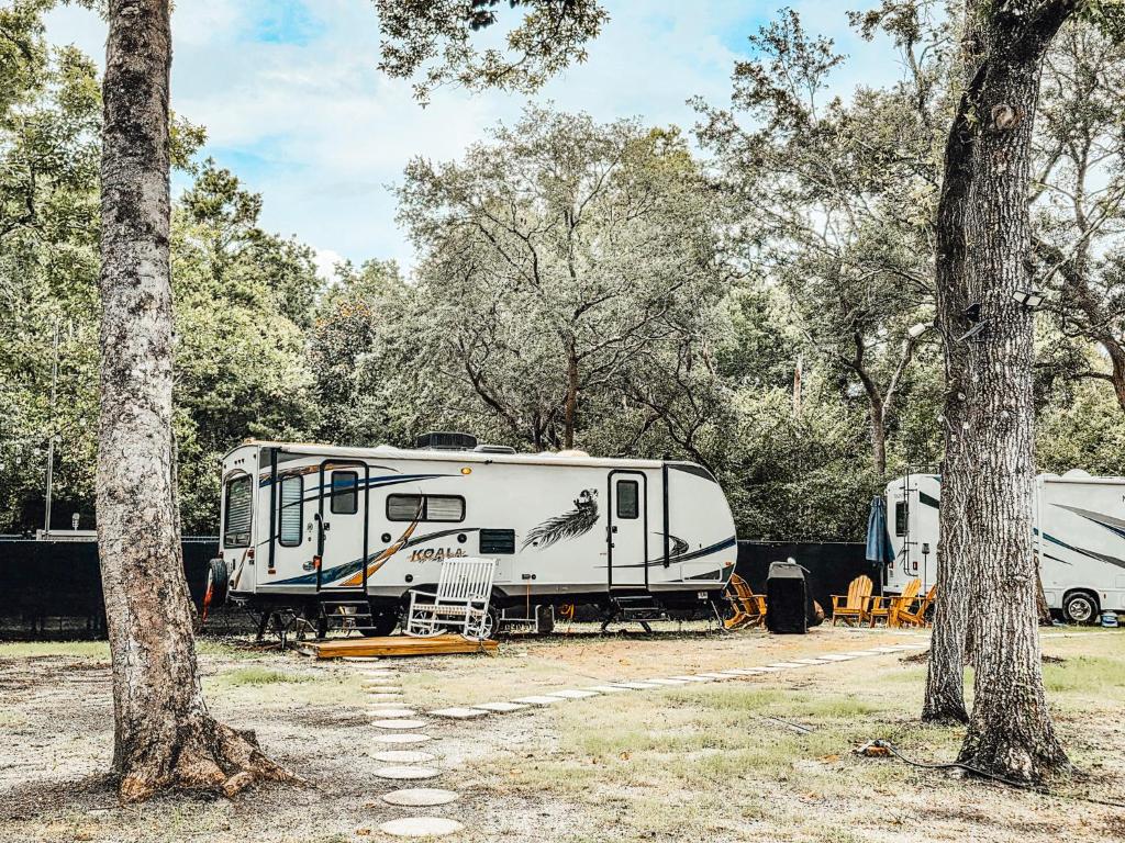 two rvs parked in a field next to trees at Nicevilles' Hidden Backyard Camper in Niceville