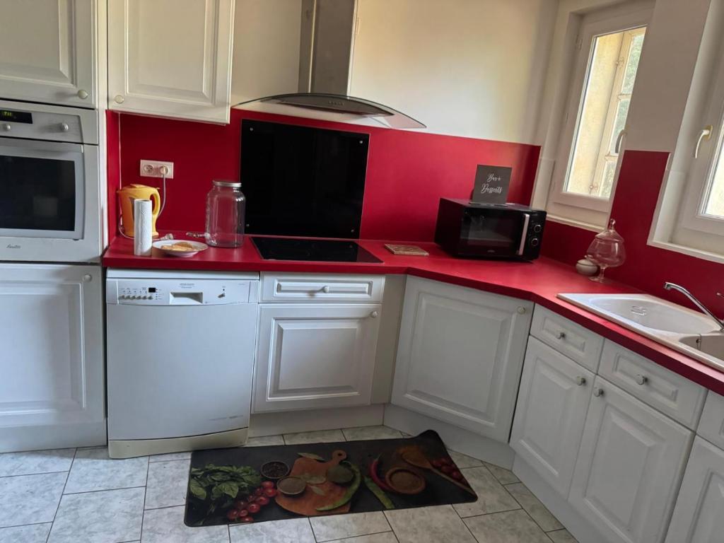 a kitchen with white cabinets and a red counter top at Chambre avec vue sur jardin et piscine in Les Angles Gard