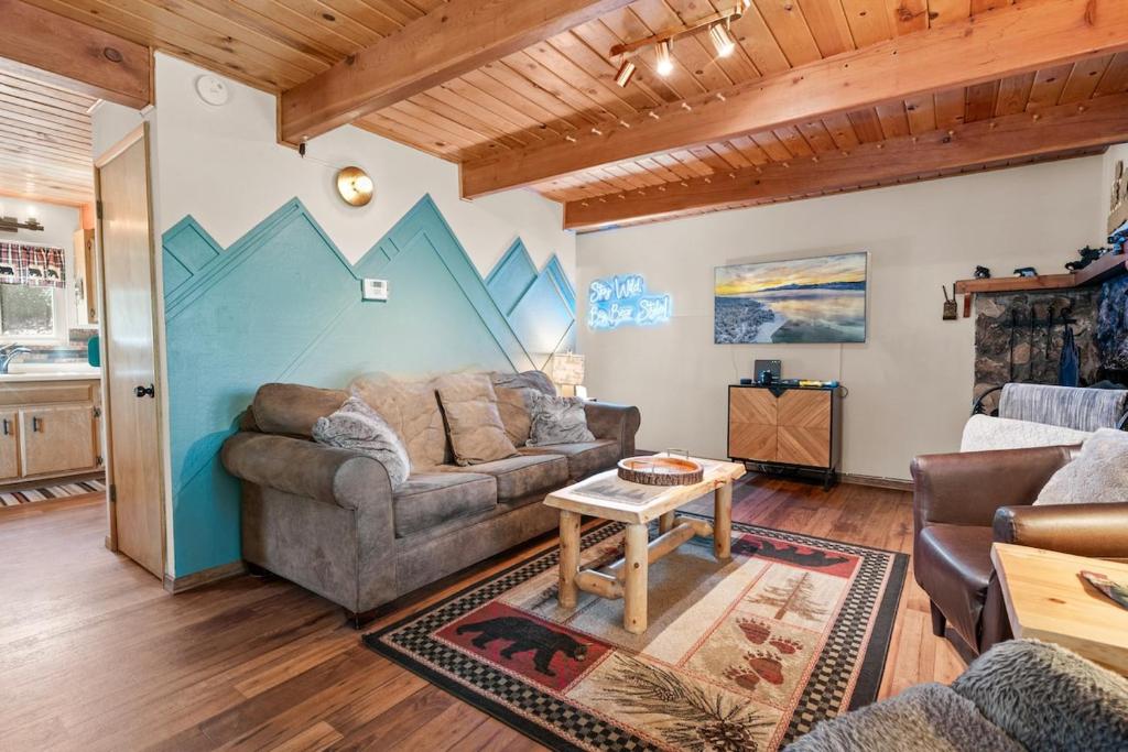 a living room with a couch and a table at Big Bear Cabin with Treetop Views 3 Decks Arcade Game, Fireplace, BBQ, WIFI in Big Bear City