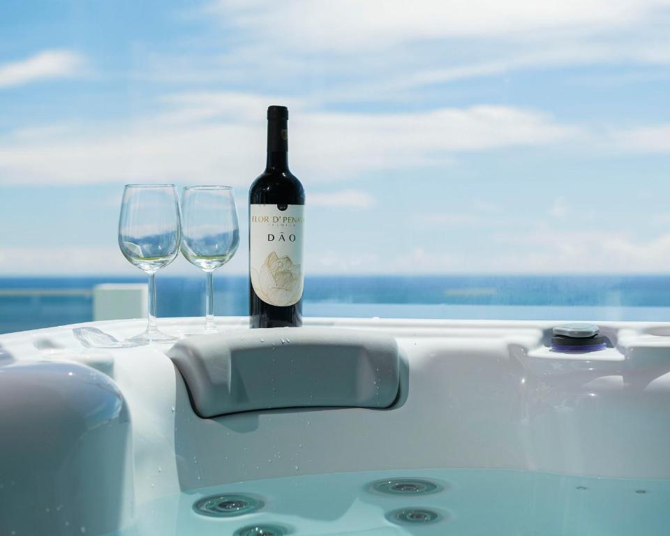 a bottle of wine sitting on a table with two glasses at Beira Da Rocha in Ponta Delgada