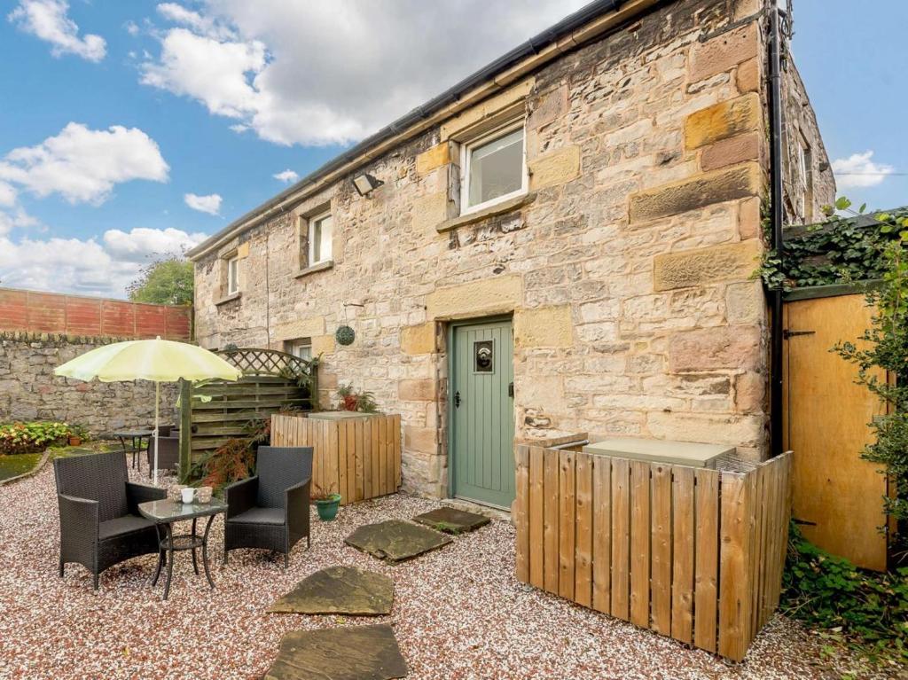un edificio de piedra con mesa, sillas y sombrilla en 1 Bed in Hartington 90126, en Hartington