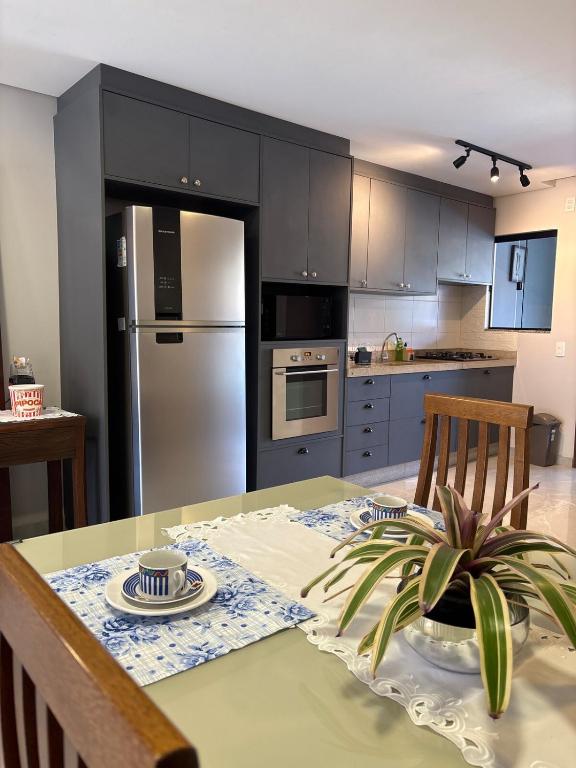 a kitchen with a table and a refrigerator at Casa Privativa Prox Expoville e Centro Com 2 Suítes in Joinville