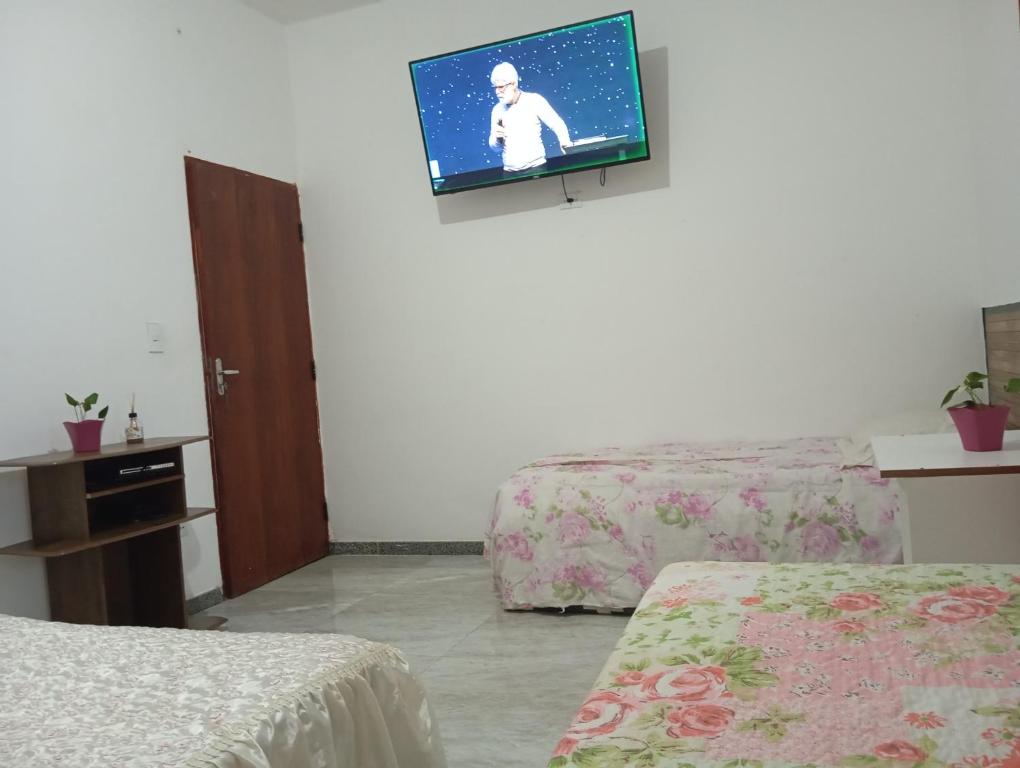 a room with two beds and a tv on the wall at Marta's house in Peruíbe
