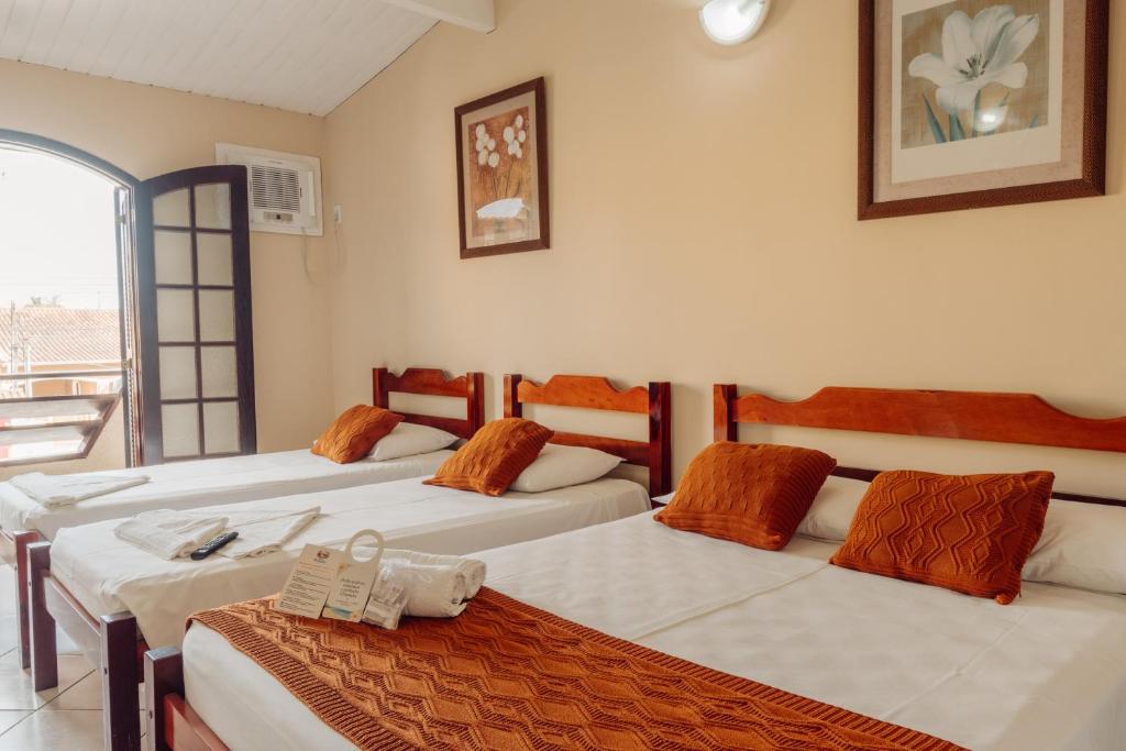 a room with three beds and a balcony at Pousada Florescer in Ubatuba