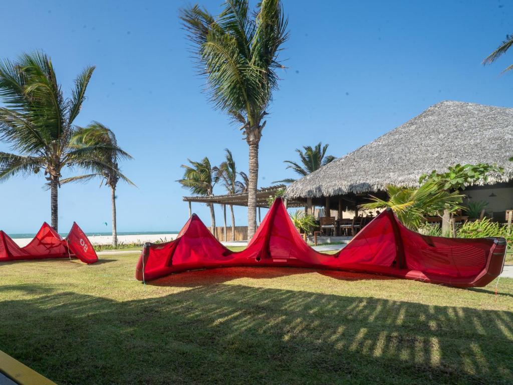 a group of red tents on the grass with palm trees at Kite Lodge Brazil in Prea
