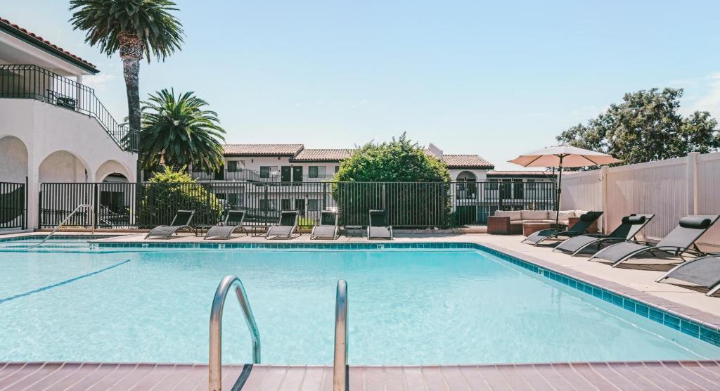 a large swimming pool with chairs and an umbrella at Sands Inn & Suites in San Luis Obispo