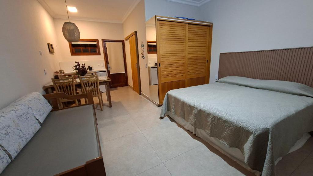 a bedroom with a bed and a table and a kitchen at FLAT ILHA FLAT HOTEL in Ilhabela