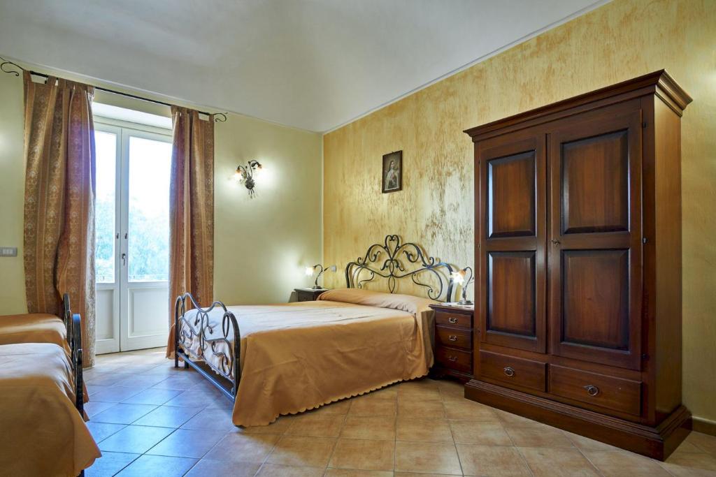 a bedroom with a bed and a cabinet and a window at Agriturismo Conte Ruggero in Centuripe