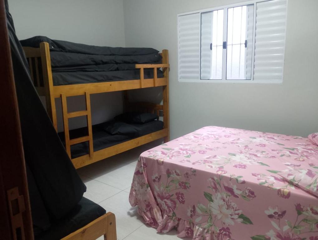 1 dormitorio con literas, 1 cama y ventana en Casa com piscina climatizada em Itanhaém!, en Itanhaém