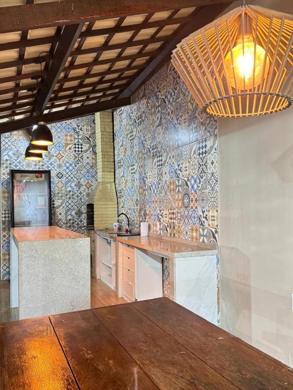 a kitchen with a wooden table and a tile wall at Casa Paraiso in Beberibe
