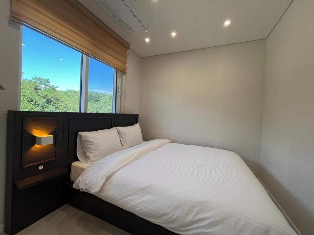 a bedroom with a white bed and a window at Gangneung Stay There in Ŭmji-mal