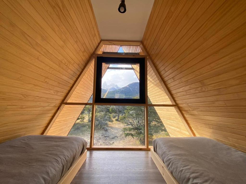 deux lits dans une chambre avec une grande fenêtre dans l'établissement OUTSCAPE l Hermosa Cabaña en Parque Nacional Cerro Castillo, à Villa Cerro Castillo