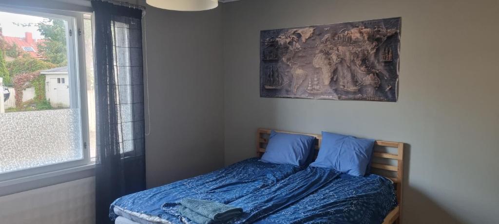 ein Schlafzimmer mit einem Bett mit blauen Laken und einem Fenster in der Unterkunft Sackleninkatu in Pori