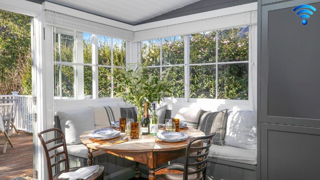 a screened in porch with a table and chairs at Werona Cottage - enchanting home in Burrawang