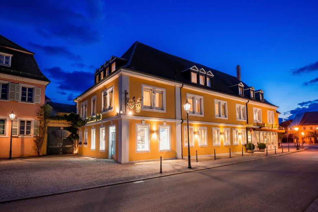 a large yellow building with lights on it at night at Hotel Adler Post in Schwetzingen