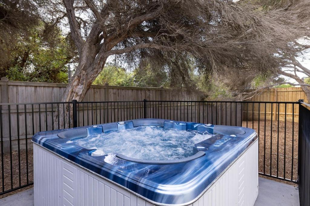 a hot tub on a fence with a tree at Original Beach Retreat in Surf Beach