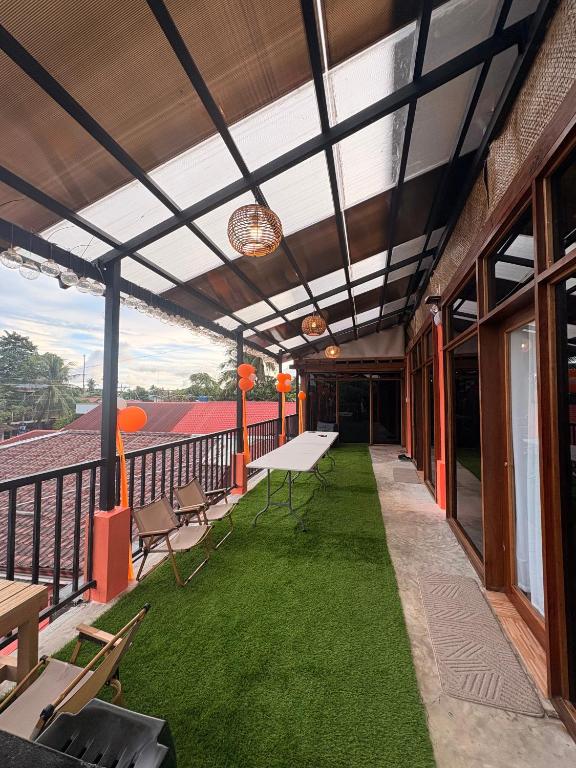 a balcony with green grass and tables and chairs at 8-Bed Mixed Dorm, Surf & Social Hostel Siargao in General Luna