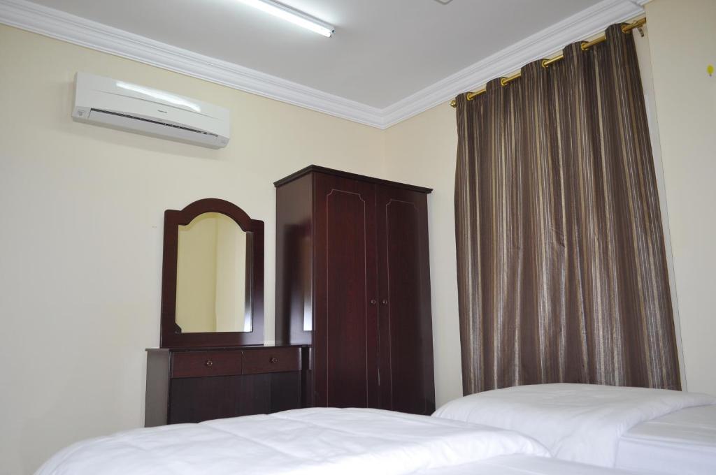 a bedroom with two beds and a dresser and a mirror at Ganaen Salalah in Salalah