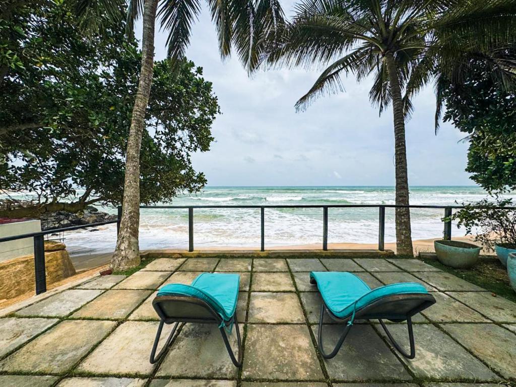 deux chaises bleues assises sur une terrasse en bois près de la plage dans l'établissement Marleys Beach House, à Talpe