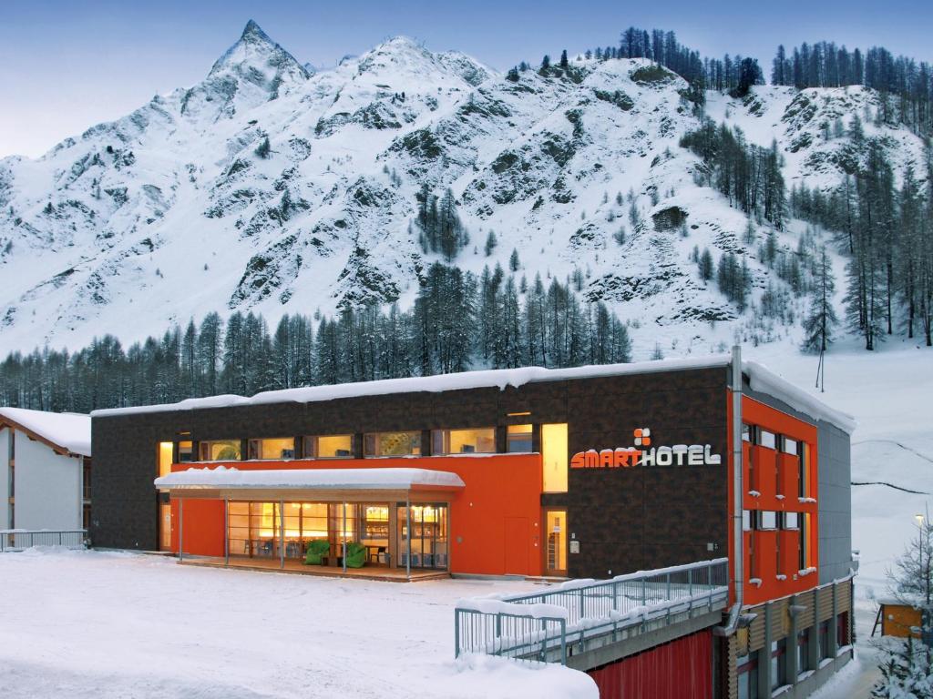 ein Gebäude vor einem schneebedeckten Berg in der Unterkunft Smart-Hotel in Samnaun