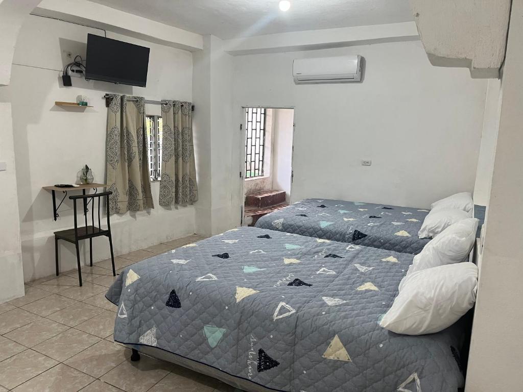 Un dormitorio con dos camas y una mesa y un televisor. en Yulis Home 1, en Retalhuleu