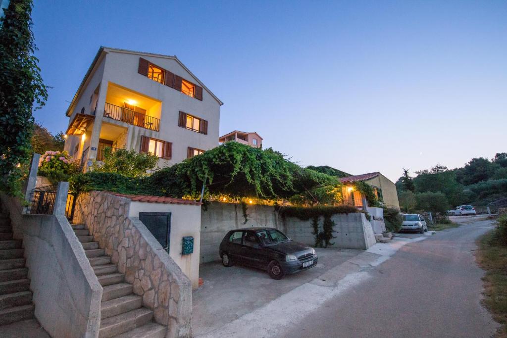 a house with a car parked in front of it at Apartments Pol Murvu in Vis