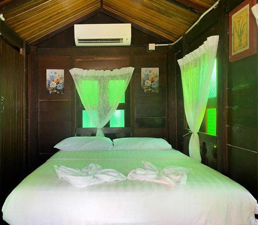 a bedroom with a large bed with green curtains at Cenanghill Beachfront in Pantai Cenang