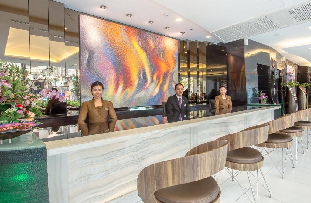 A staffed reception bar with high stools, mirrored walls, and a large illuminated artwork.