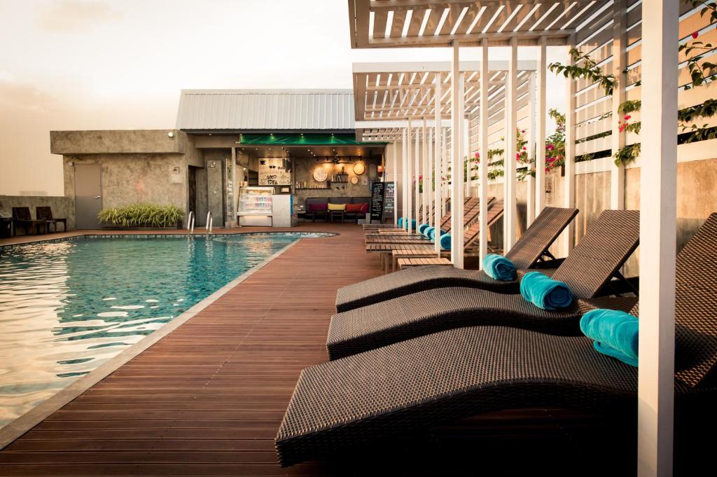 A rooftop pool deck lined with chaise lounges beside the hotel building.