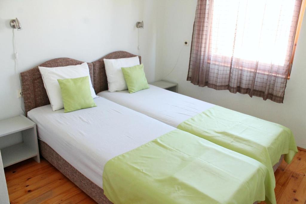 two beds in a small room with green pillows at Apartments Villa Milna 1 in Budva