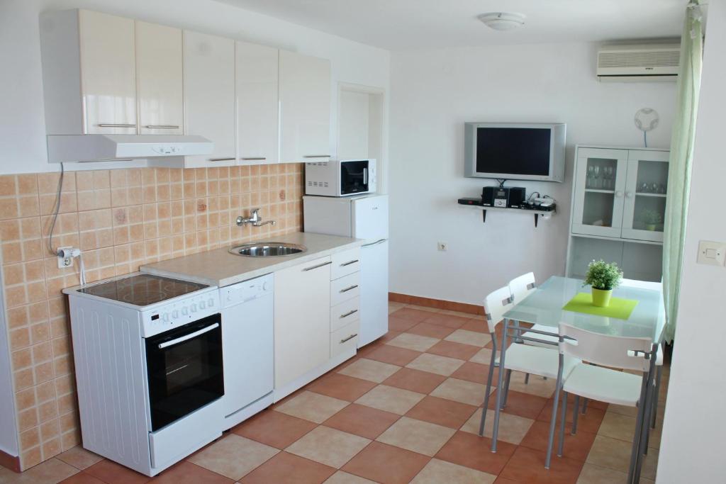 a kitchen with white cabinets and a table and a television at Apartments Villa Milna 1 in Budva