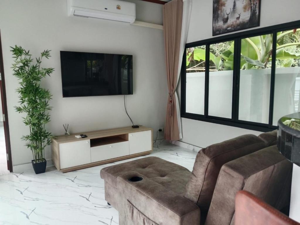 a living room with a couch and a flat screen tv at Kannaphat Villa in Ko Phangan