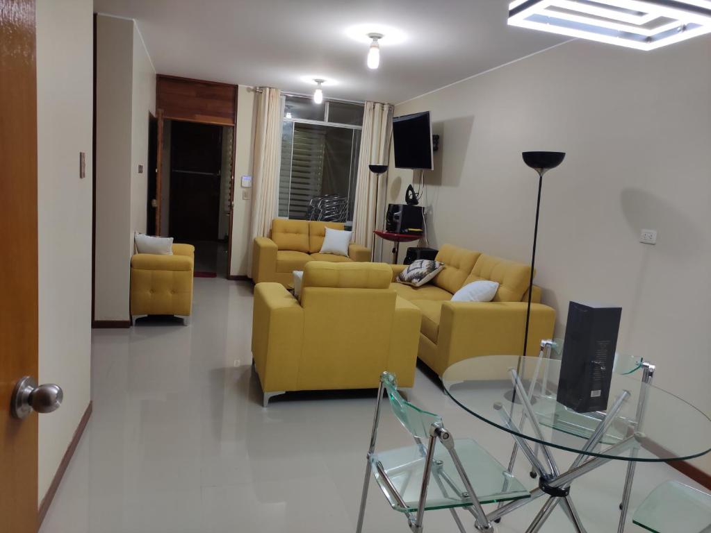 a living room with yellow couches and a glass table at Casa Oasis Meneses in Ica